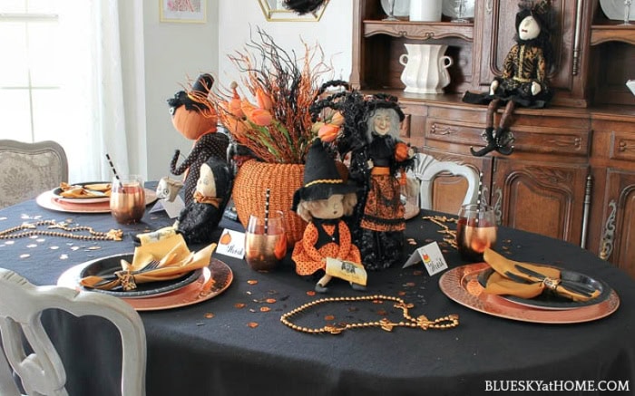 A dining table decorated for Halloween in a copper and orange themed tablescape.  The theme features a very large DIY Halloween 