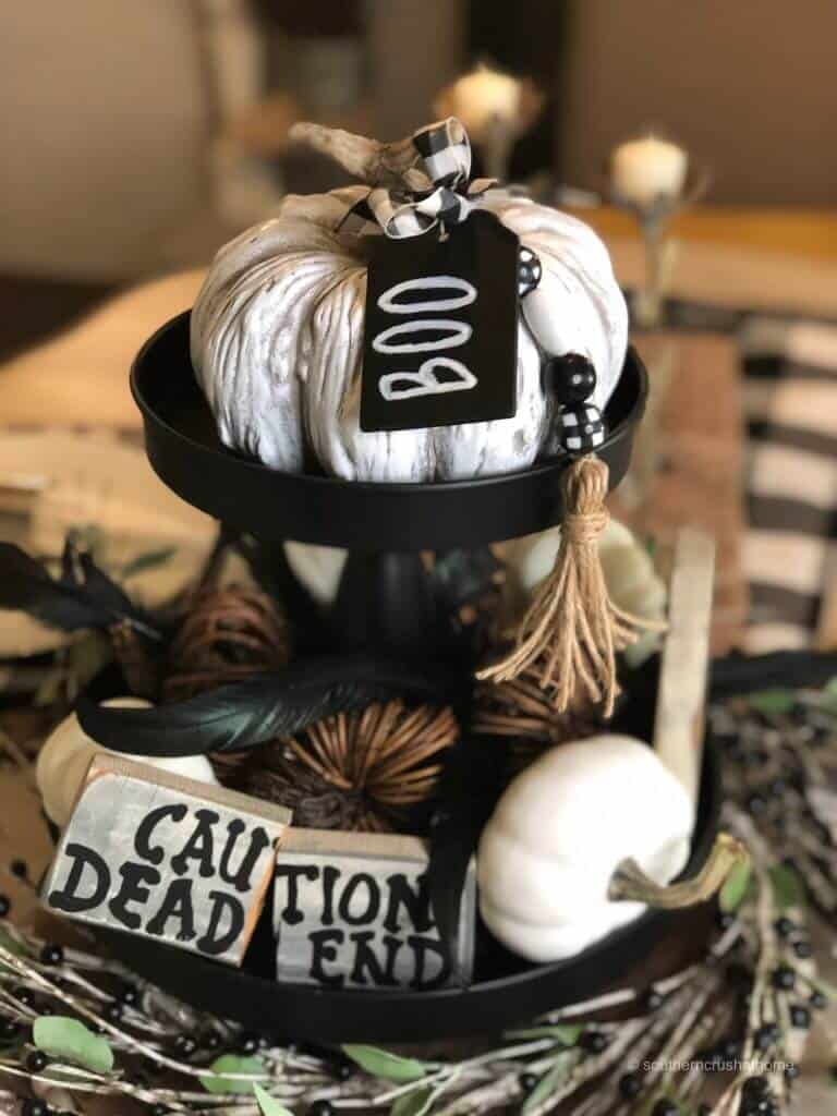 A tiered tray in black and white for Halloween, there is a caution dead end sign, white pumpkins and large white pumpkin with a Boo tag.