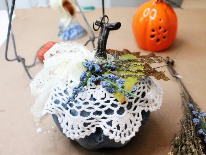 Adding dried blue flowers and twigs to a dollar tree blue pumpkin.