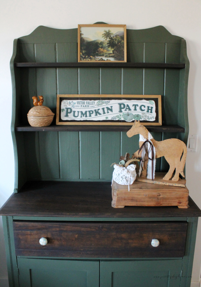 The top of a vintage furniture makeover of an old cabinet the final picture.  It is painted bayberry green with dark chocolate shelves, top and drawer front.  The back has been refinished with tongue and groove and painted green to match.