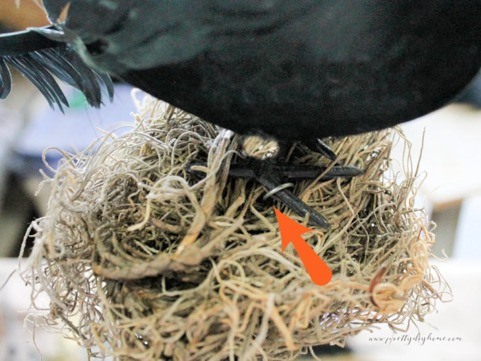 Attaching a crow to the top of the witch wand, an arrow showing the wire placement.