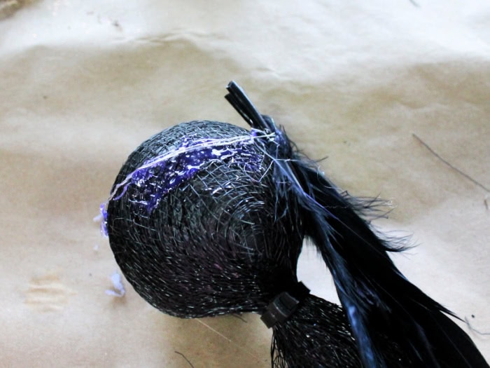 A bundle of feathers attached t the top of a witch wand base, with twisted floriest wire and hot glue.