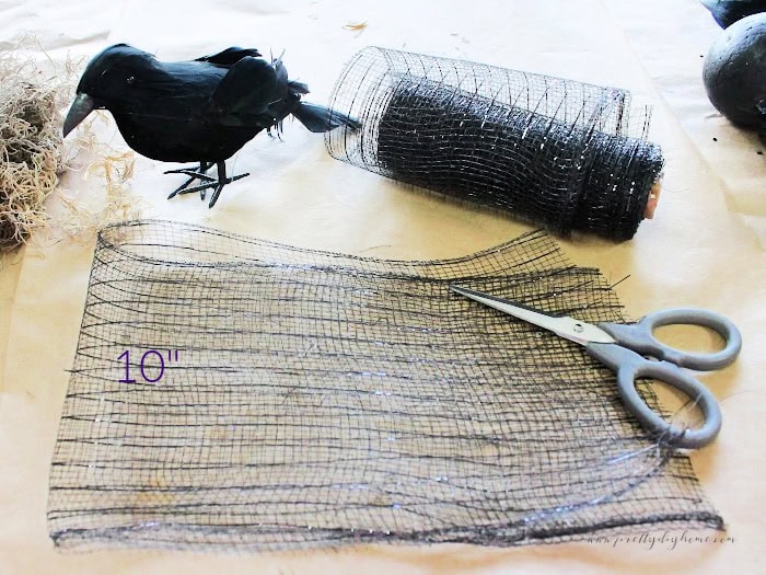 Cutting tow pieces of mesh for wrapping around a styrofoam ball for a witch wand for Halloween.