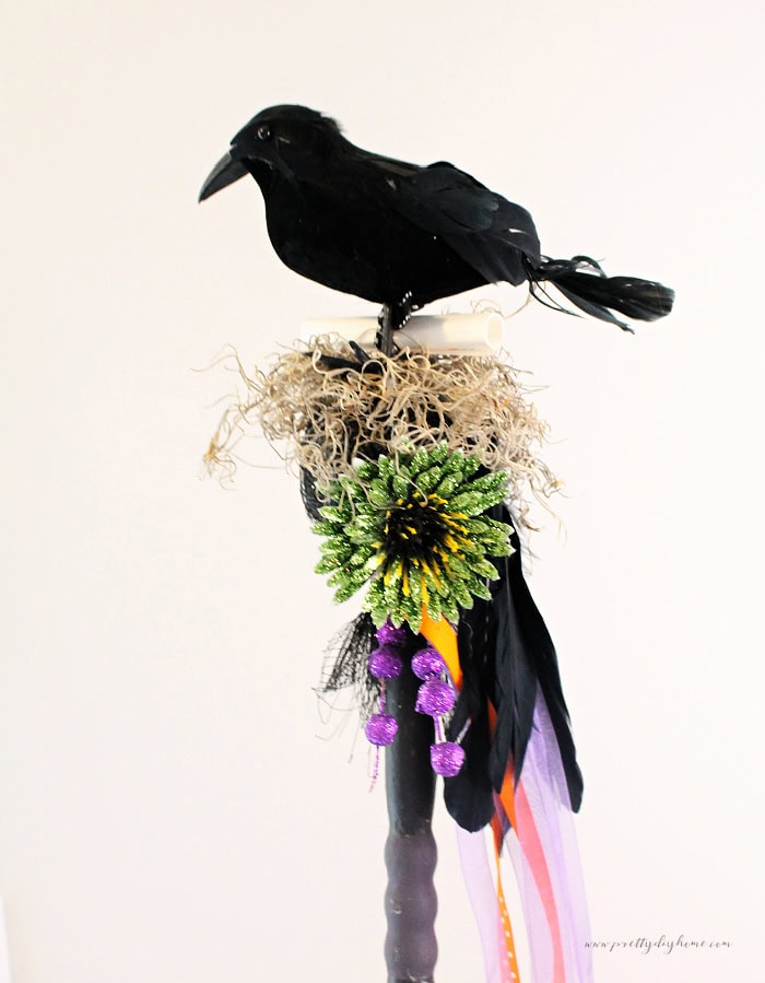 A colorful DIY witchwand with a black crow on the top.