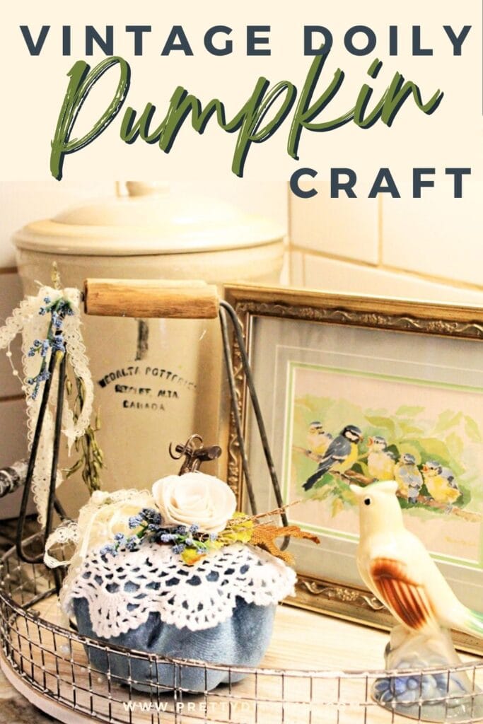 A blue dollar tree pumpkin fall craft, decorated with a small vintage handmade doily. Then decorated with leaves, flowers and lace. Its part of a fall decor for in the kitchen with a vintage bird, vintage crock, and vintage bird picture in a gold frame.