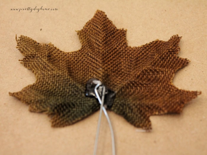 Adding wire to the back of a large pumpkin leaf for a Dollar Tree pumpkin craft.
