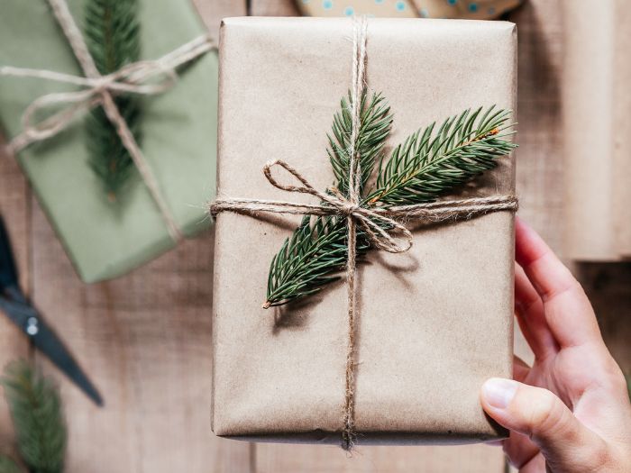 Christmas gift wrapped in brown kraft paper with twine and a fresh evergreen sprig, simple farmhouse style wrapping idea.