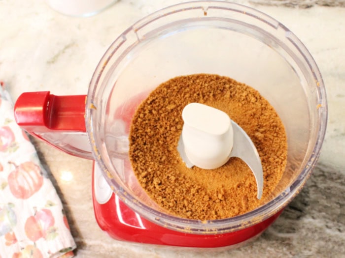 A food processor filled with fine gingersnap cookie crumbs for making granola.