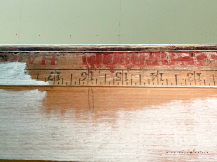 An old ruler stuck inside an antique cabinet to brace it.  You can see the lettering for measurements.