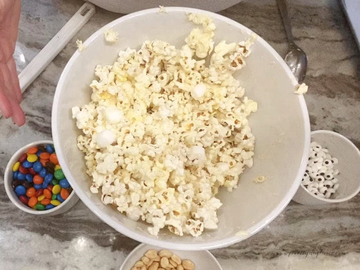 A large bowl of popcorn covered with puffy mini marshmallows.  They are puffy not melted.