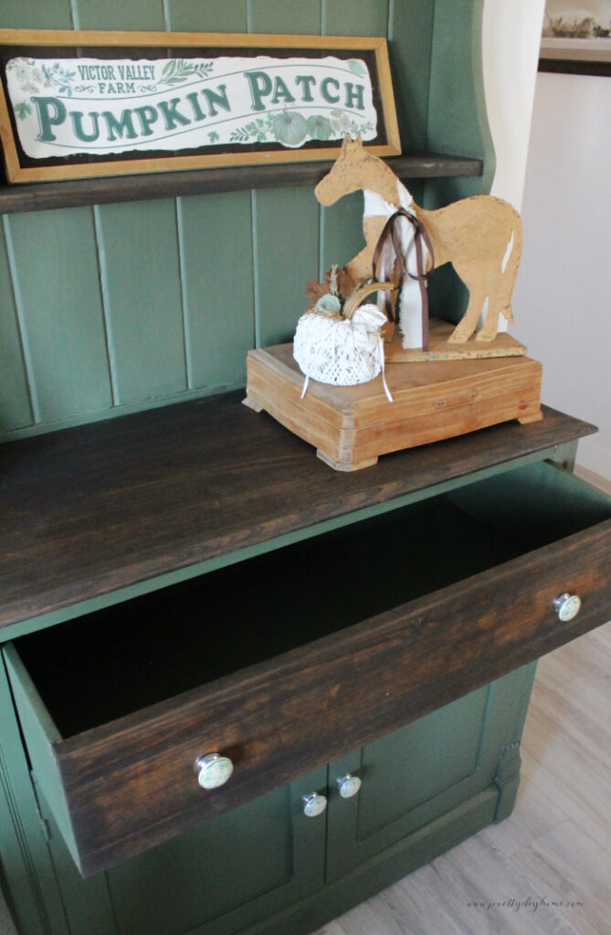 A finished vintage furniture makeover cabinet with the drawer open showing that the inside of the cabinet has been painted green.