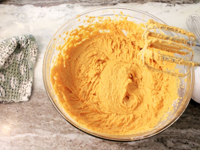 A bowl full of beautiful orange pumpkin bread batter.