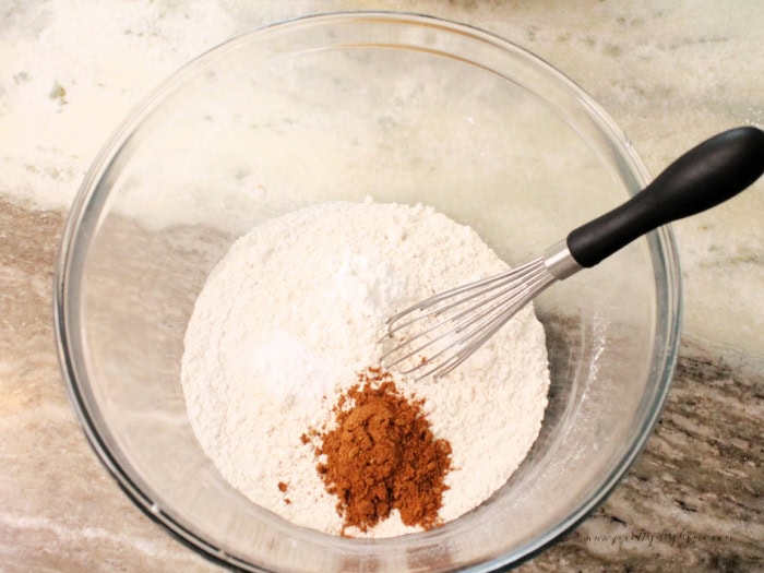 A large clear bowl filled with flour, baking soda, baking powder, and pumpkin spice.