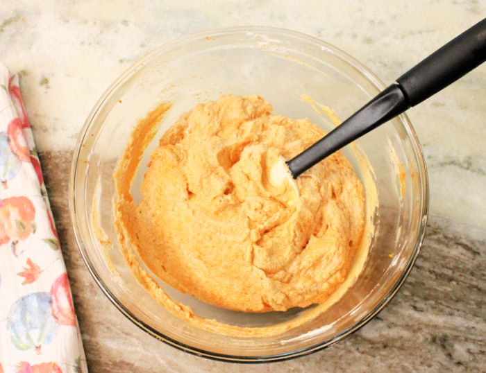 A clear bowl full of light and fluffy pumpkin mousee before its placed in the fridge.