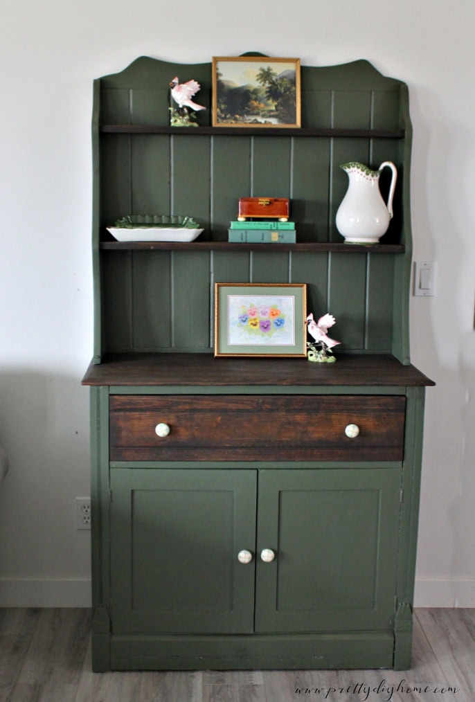 A diy furniture makeover all finished witrh dark green bayberry paint and chocolate stain. The vintage cabinet has two doors and a large drawer on the bottom, the top had three shelves with stained shelving.