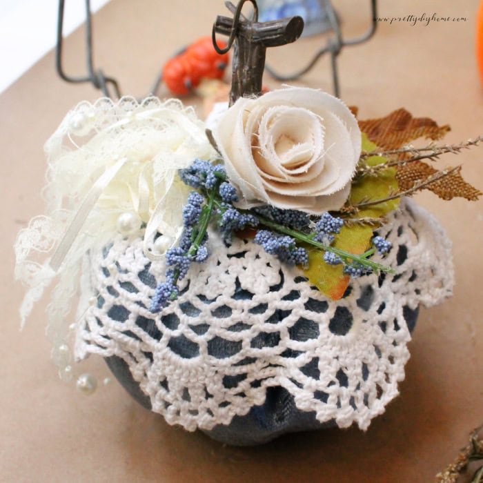 A Dollar Tree pumpkin craft decorated with a vintage doily, dried flowers, lace ribbon and a rag rolled rose.