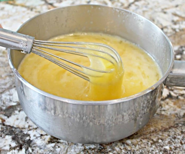 Eggs being whisked in a saucepan on the counter while starting to make homemade advocaat.