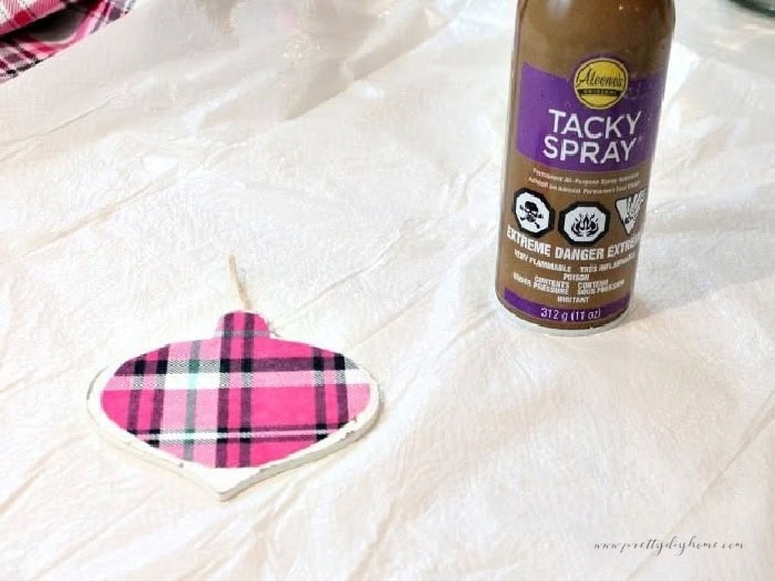 Pink flannel covered ornament beside a can of tacky spray on a white sheet used to protect the work surface.