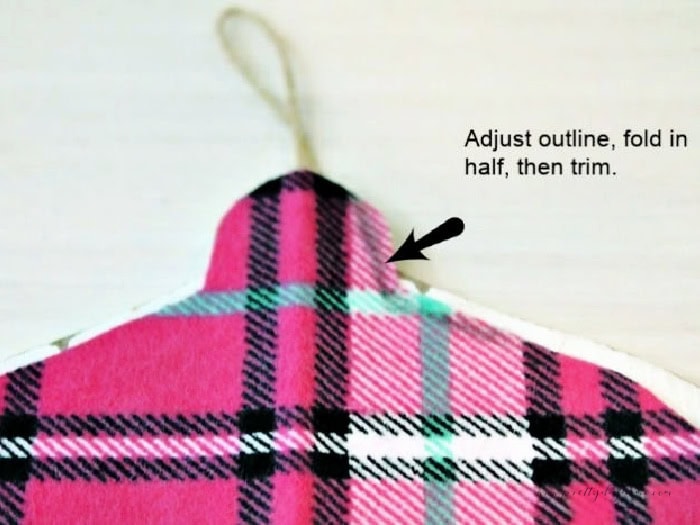 Fitting pink flannel fabric onto a wooden ornament form to make a DIY Christmas ornament.