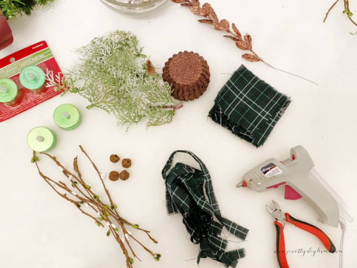 Supplies for making tart tin candles ornaments, metal tins, gteenery, flameless candles, tartan ribbon, and little rusty Christmas bells.