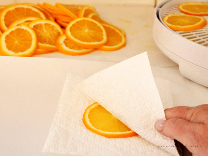 Blotting each orange slice with a paper towel before placing it in the dehydrator.