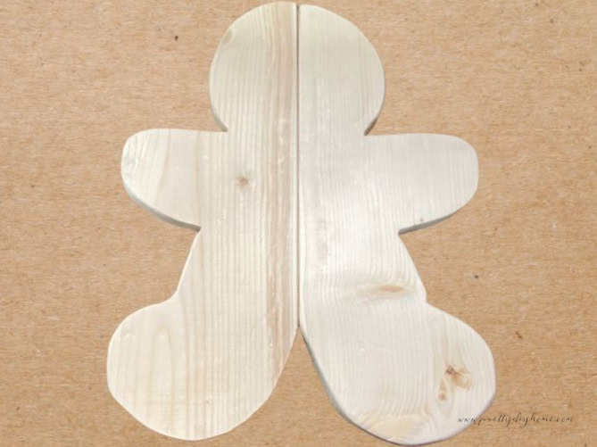 Sanded wooden gingerbread man halves aligned in the center to check for symmetry before gluing.
