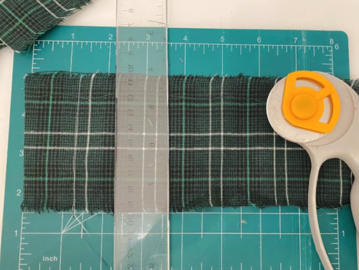 Cutting tartan fabric to line the inside of a tart tin ornament for a handmade vintage Christmas craft.