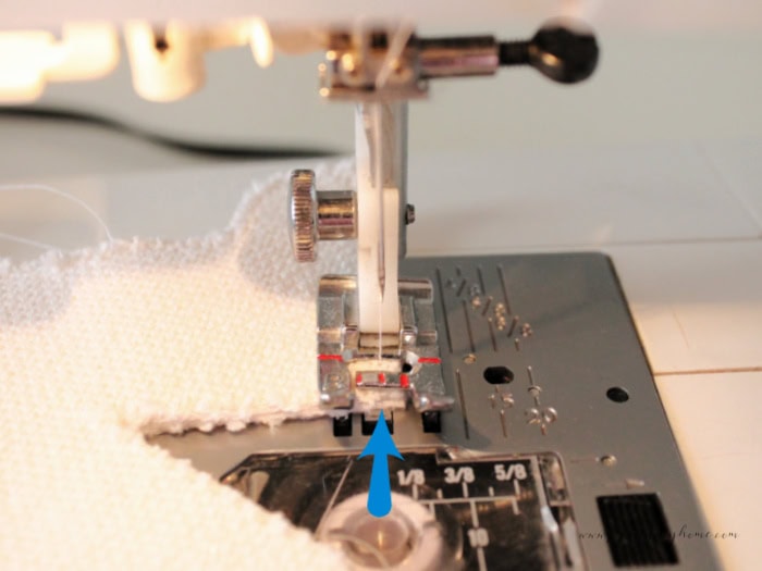 Sewing a narrow seam around the edge of a fabric gingerbread man on a sewing machine.