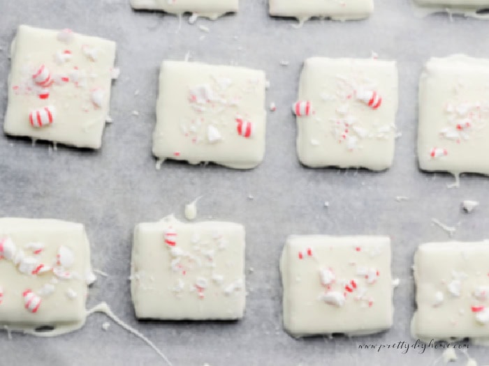 White chocolate covered graham crackers on parchment paper, ready for peppermint topping.