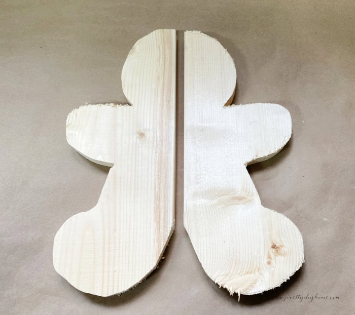 Two halves of a wooden gingerbread man cut from scrap wood, lined up side by side before joining together, not yet sanded.