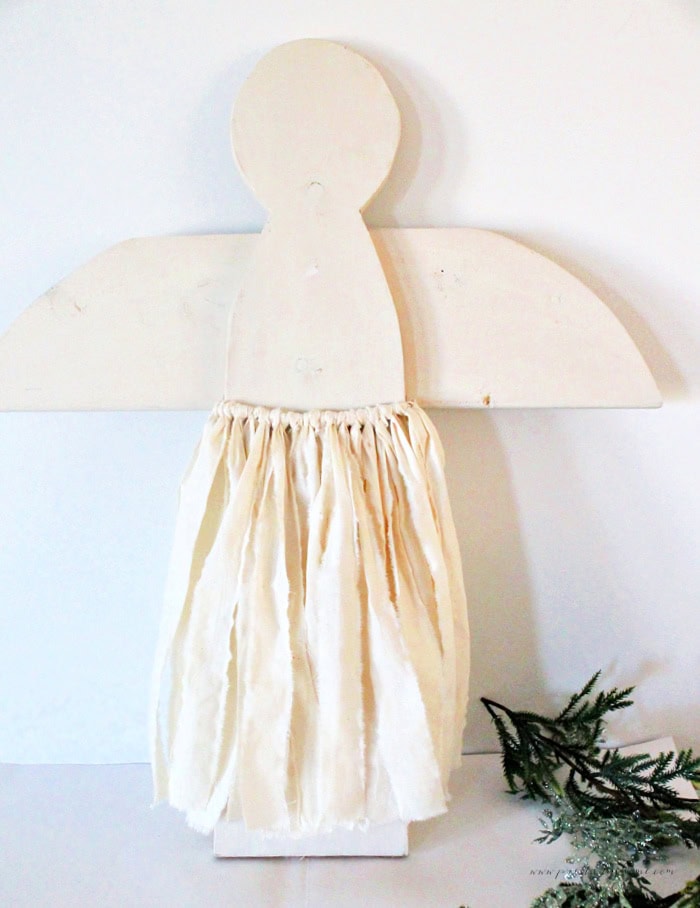 Large wooden Christmas angel with the first muslin skirt layer attached, showing the soft frayed fabric before adding tulle and ribbon.