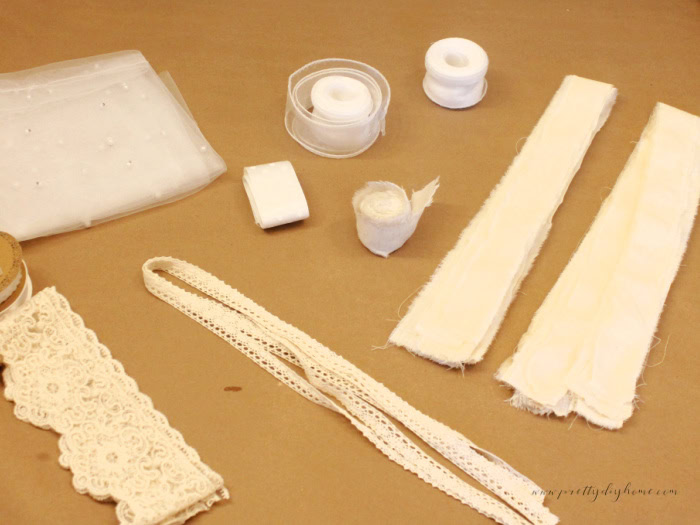 Supplies for the angel’s skirt, including muslin strips, pearl tulle, cotton lace, and ribbon in soft white and green cottage core colors.