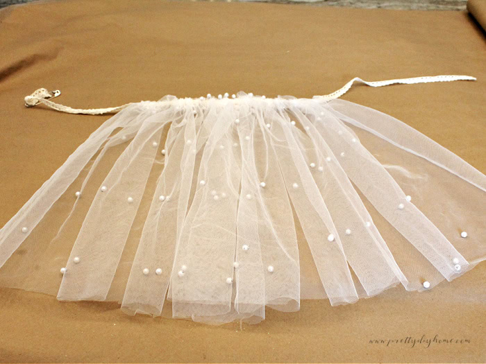 Pearl tulle skirt panel laying flat after sewing the top drawstring lace, ready to be tied as the second layer of the wooden Christmas angel’s skirt.
