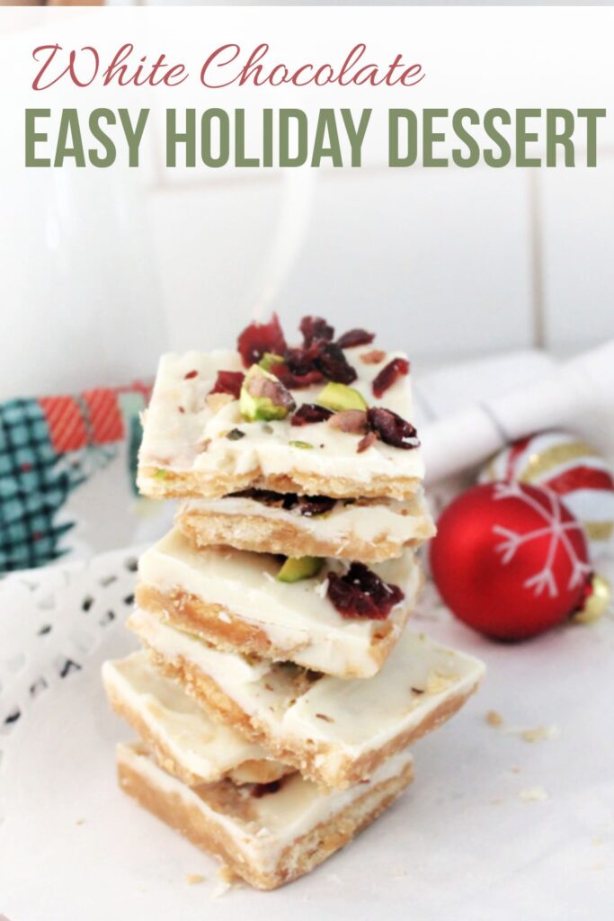 White chocolate Ritz cracker tofee stacked on a plate with pistachios and cranberries on top.