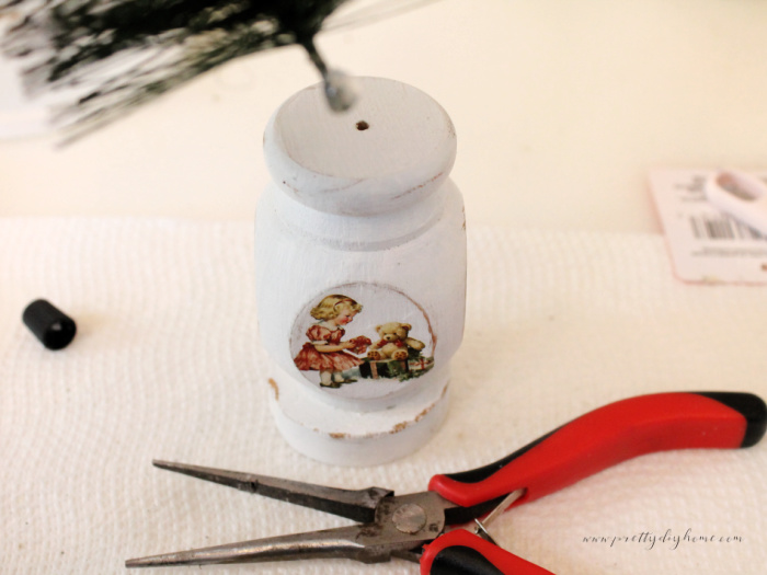 Adding the wire stem of a bottle brush tree into the drilled hole on top of a painted spindle.