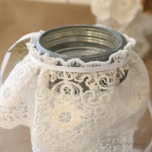 Adding a thin white ribbon around gathered lace on a mason jar for Christmas decor.