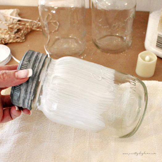 Applying Mod Podge to a mason jar before adding Epsom salt frost.