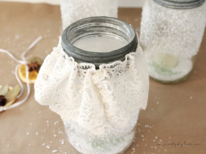 Gathering and tying vintage lace around a mason jar for a Christmas centerpiece/