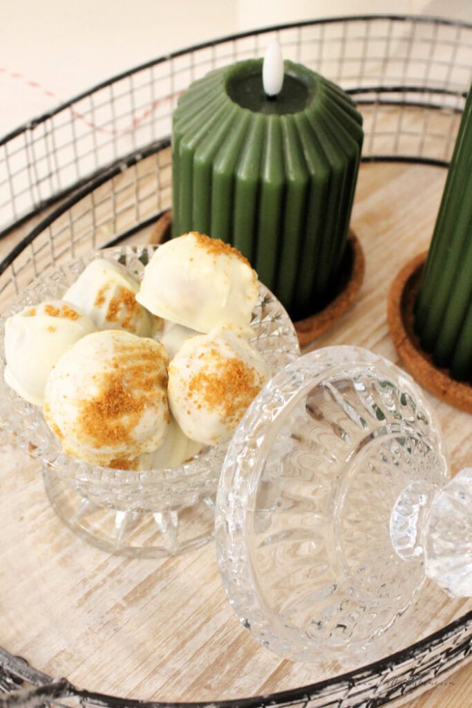 Gingerbread truffles served in a vintage crystal candy dish beside green candles.