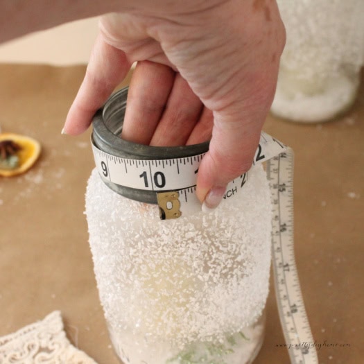 Measuring the circumference of a mason jar with a tape for lace wrapping.