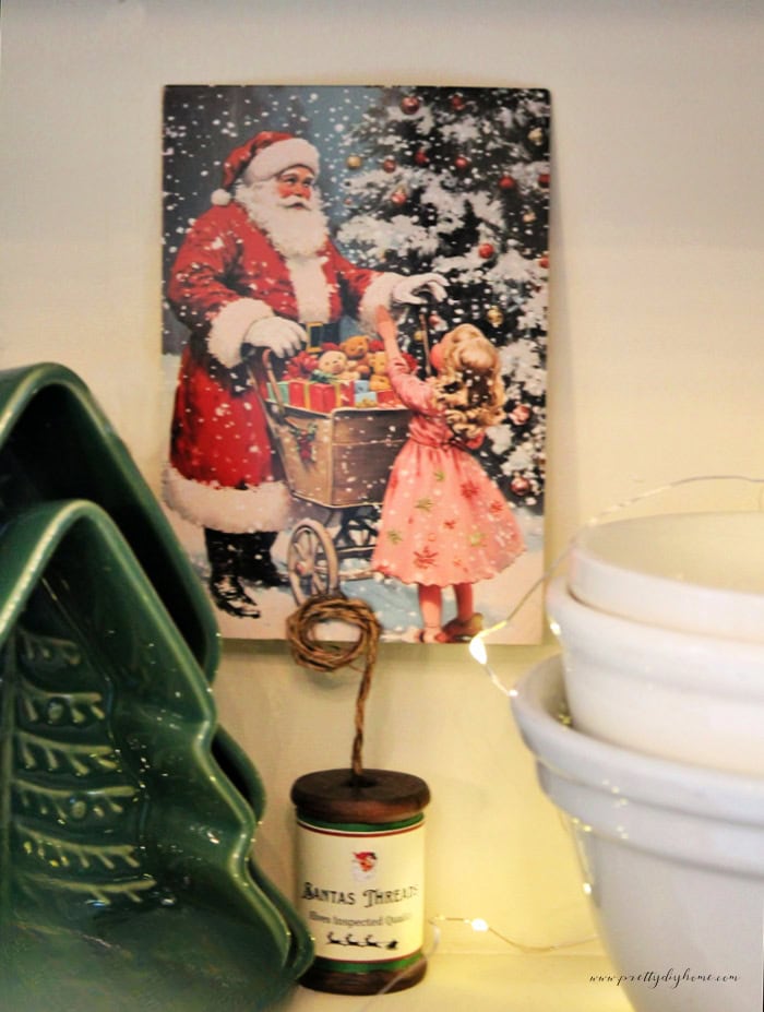 Close up of a Santa postcard displayed in a wire holder made from a wooden thread spool.