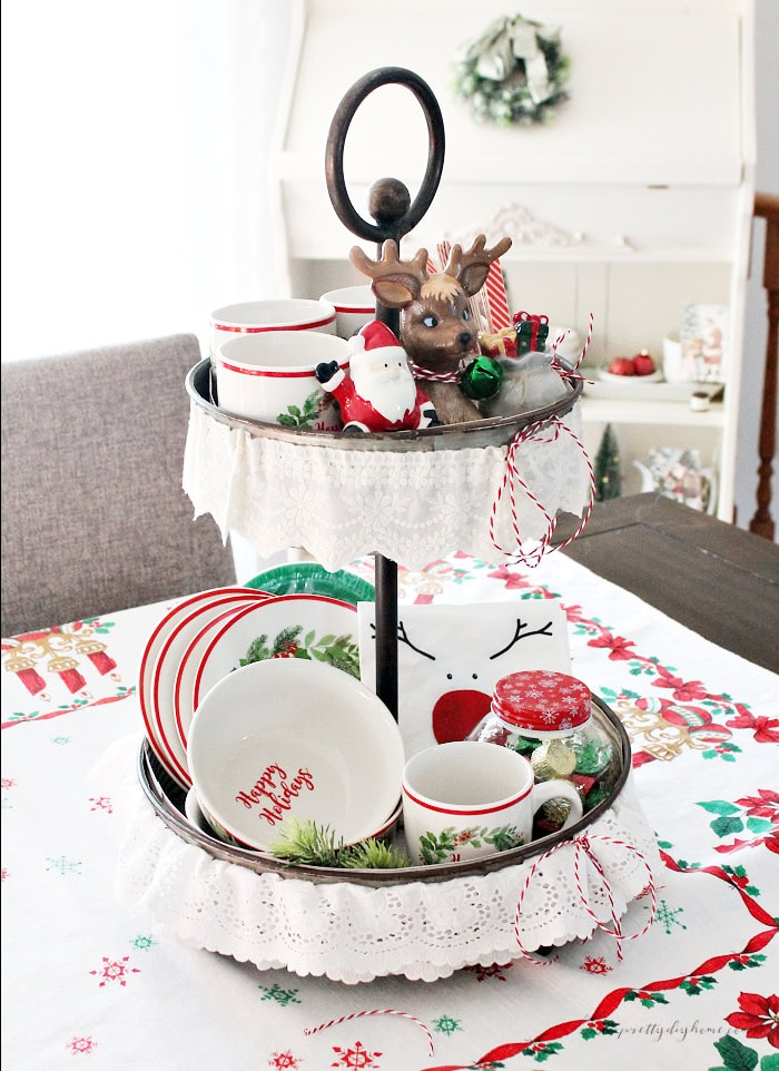 Full-length view of a vintage Christmas tiered tray centerpiece decorated with festive mugs, bowls, and seasonal accents.