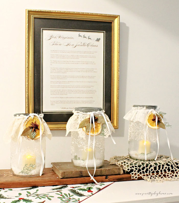 Right-angle view of vintage mason jar Christmas centerpiece with lace and candlelight.