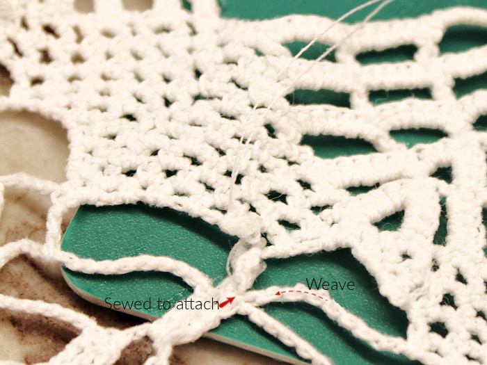 Mending a vintage doily by weaving thread through crochet stitches for a doily craft table runner