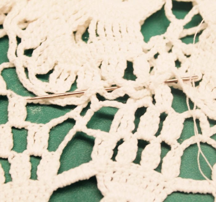 Close up of stitching vintage doilies together along the edges for a doily craft table runner