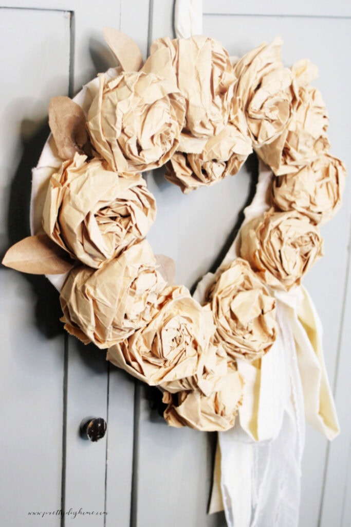 Finished paper bag rose wreath with fabric bow shown at an angle.