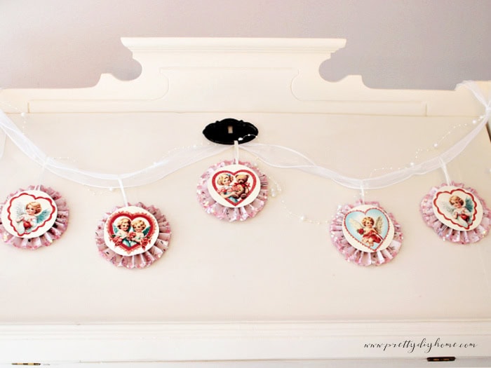 Vintage Valentine paper medallion banner with five cupid medallions displayed in a straight-on view