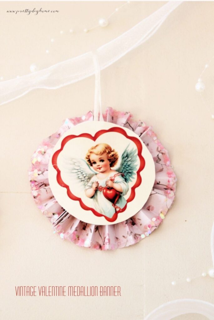 Vintage Valentine paper medallion banner with cupid center, ribbon hanger, and pearl details