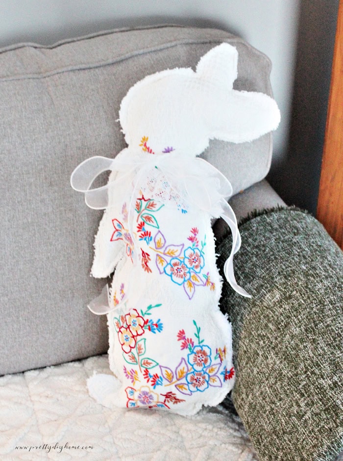 DIY Easter bunny made from repurposed vintage linens with a white bow sitting on a couch