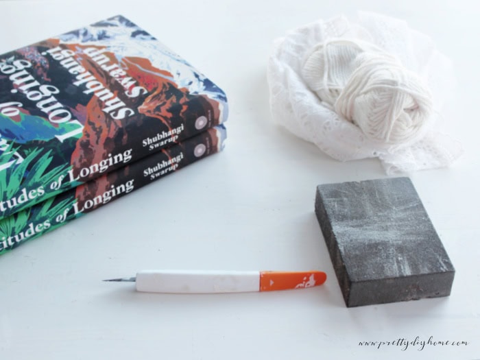 Supplies for making decorative vintage book stacks including hardcover books, ribbon, twine, and pressed dried flowers